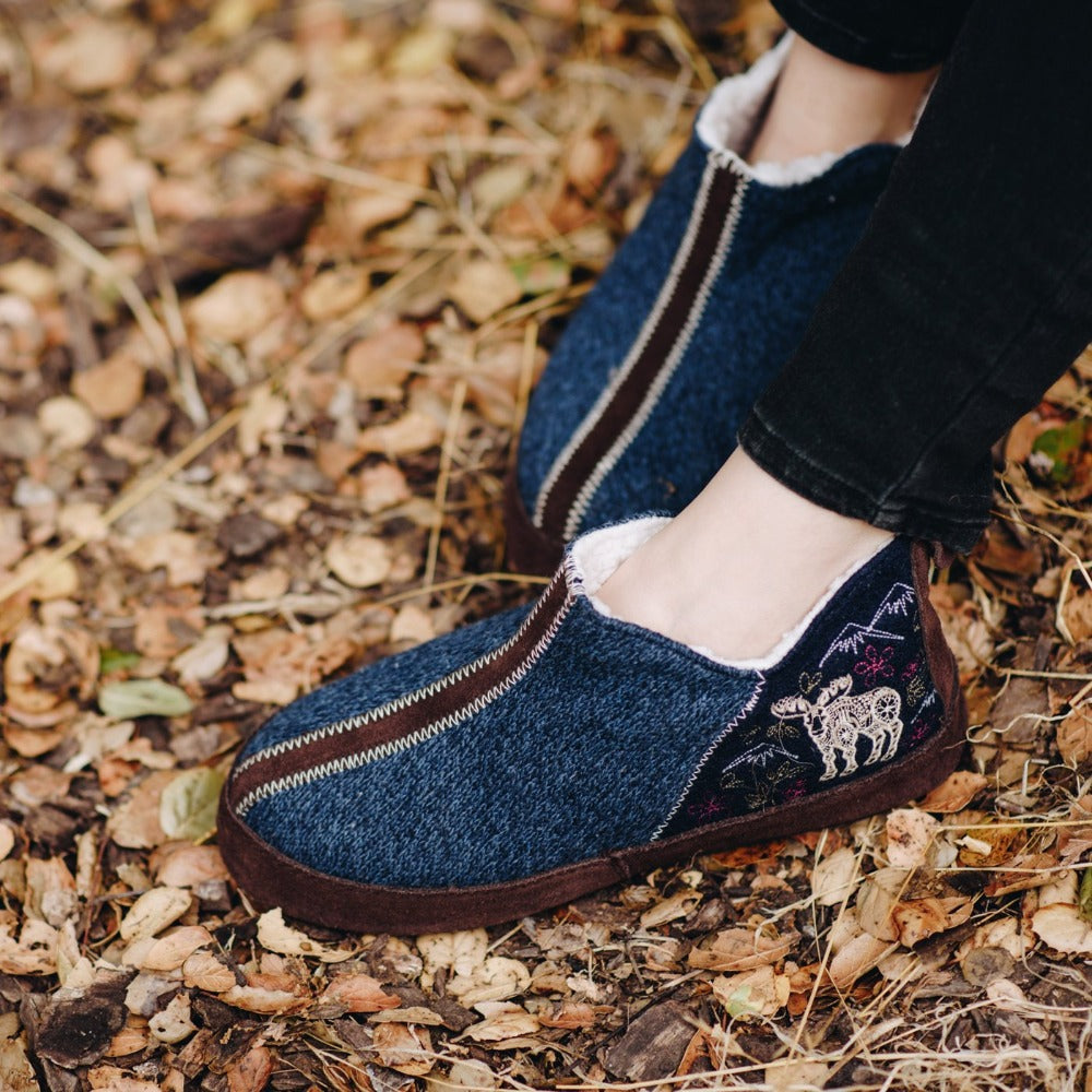 Women's Forest Bootie Slippers in Navy Moose on Model in a Bed of Leaves#color_navy-moose