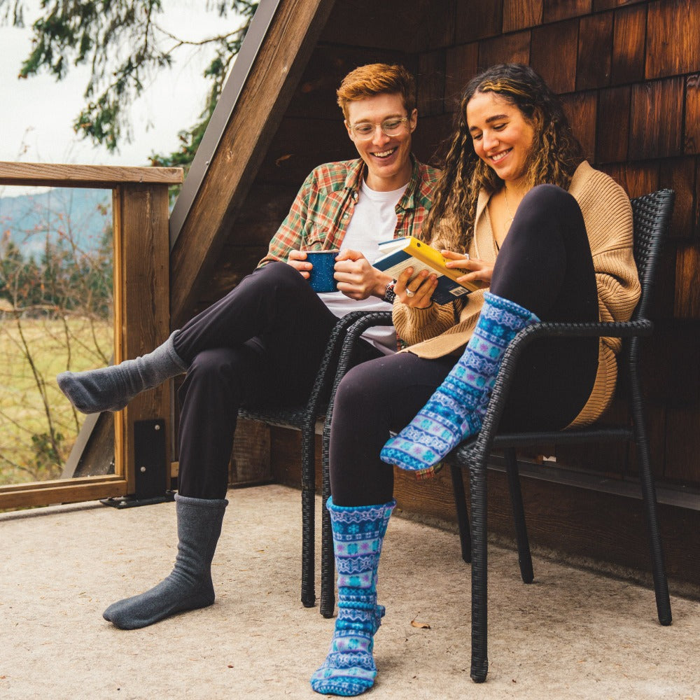 Couple sitting out on a porch wearing the Charcoal and Icelandic Blue Versafit socks. Reading and sipping coffee.#color_olive