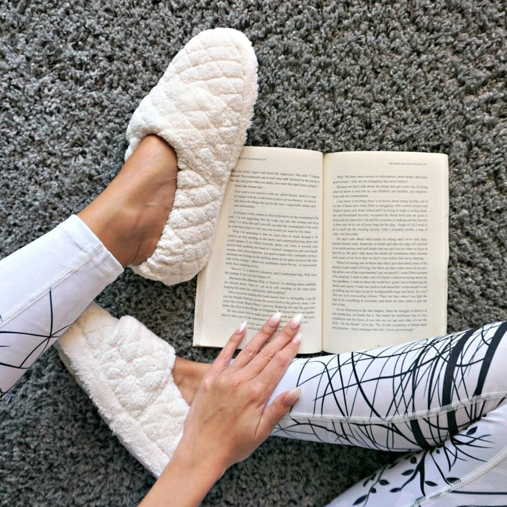Women's Adjustable Spa Wrap Slippers in Natural on model sitting on a plush rug reading a book#color_natural