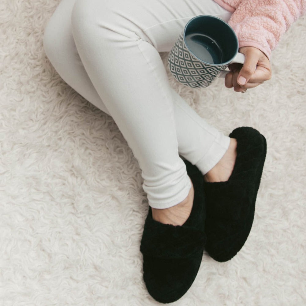 Women's Adjustable Spa Wrap Slippers in Black On Model Sipping Coffee on Fur Rug#color_black