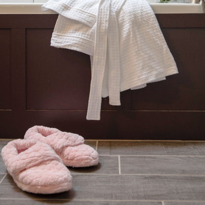 Women's Adjustable Spa Wrap Slippers in pink off figure sitting in front of bath tub#color_pink