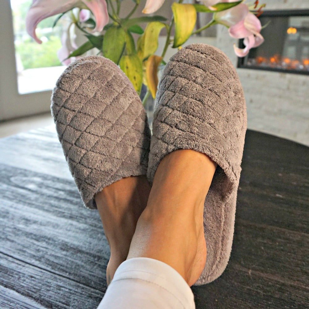 Women's Spa Quilted Clog in Grey on Figure with feet up on dining table with flowers and fireplace in the background#color_grey