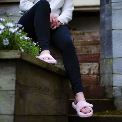 Women's Spa Slide Slippers in Pink on Model sitting on a flower box with their feet dangling#color_pink