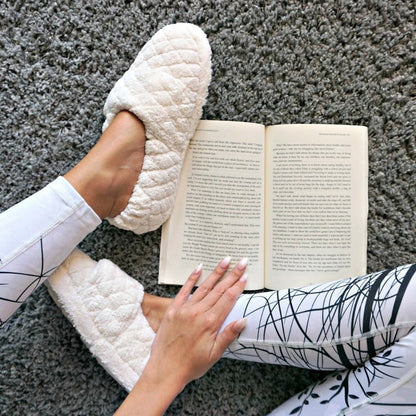 Women's Adjustable Spa Wrap Slippers in Natural on model sitting on a plush rug reading a book#color_natural